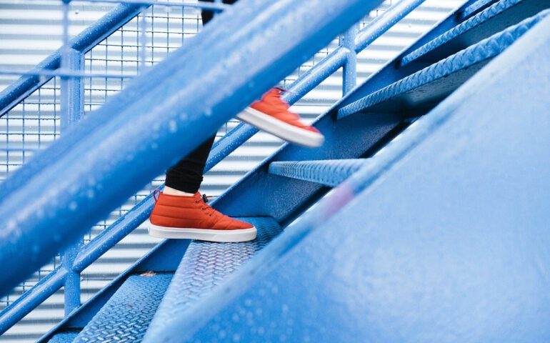 Treppen und Mensch mit roten Schuhen geht die Stufen hoch