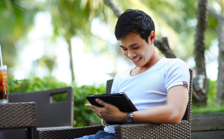 Lachender Mann mit I Pad sitzend