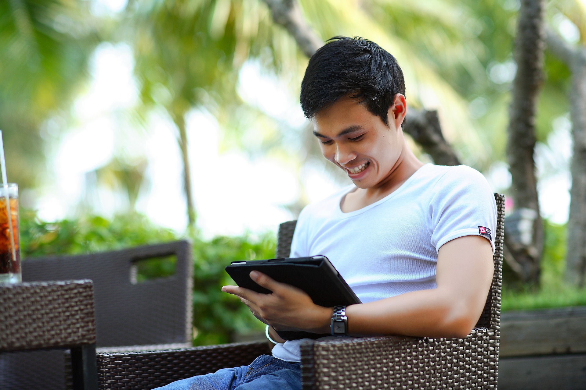 Lachender Mann mit I Pad sitzend